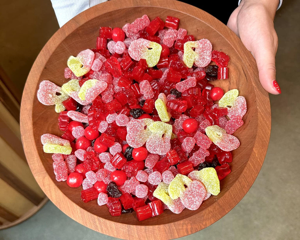 Bowl of mixed Halloween candy featuring cherry gummies, sour twin cherries, licorice bites, and other red and yellow treats, creating a colorful candy salad