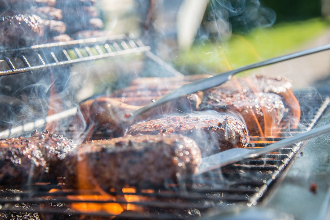 A close up photo of meat being barbecued on a griddle