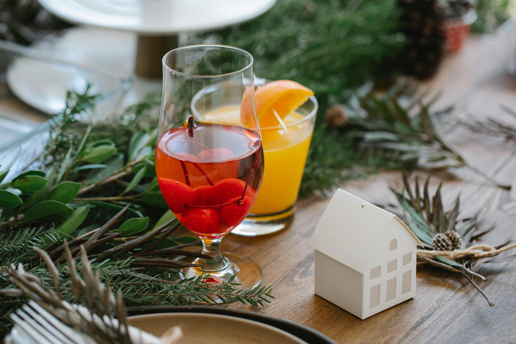 A glass of tart cherry juice with whole cherries, set on a rustic table with holiday decor