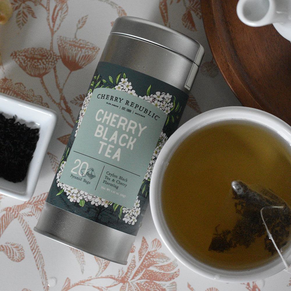 A tin of Cherry Republic cherry black tea next to a cup of freshly brewed tea