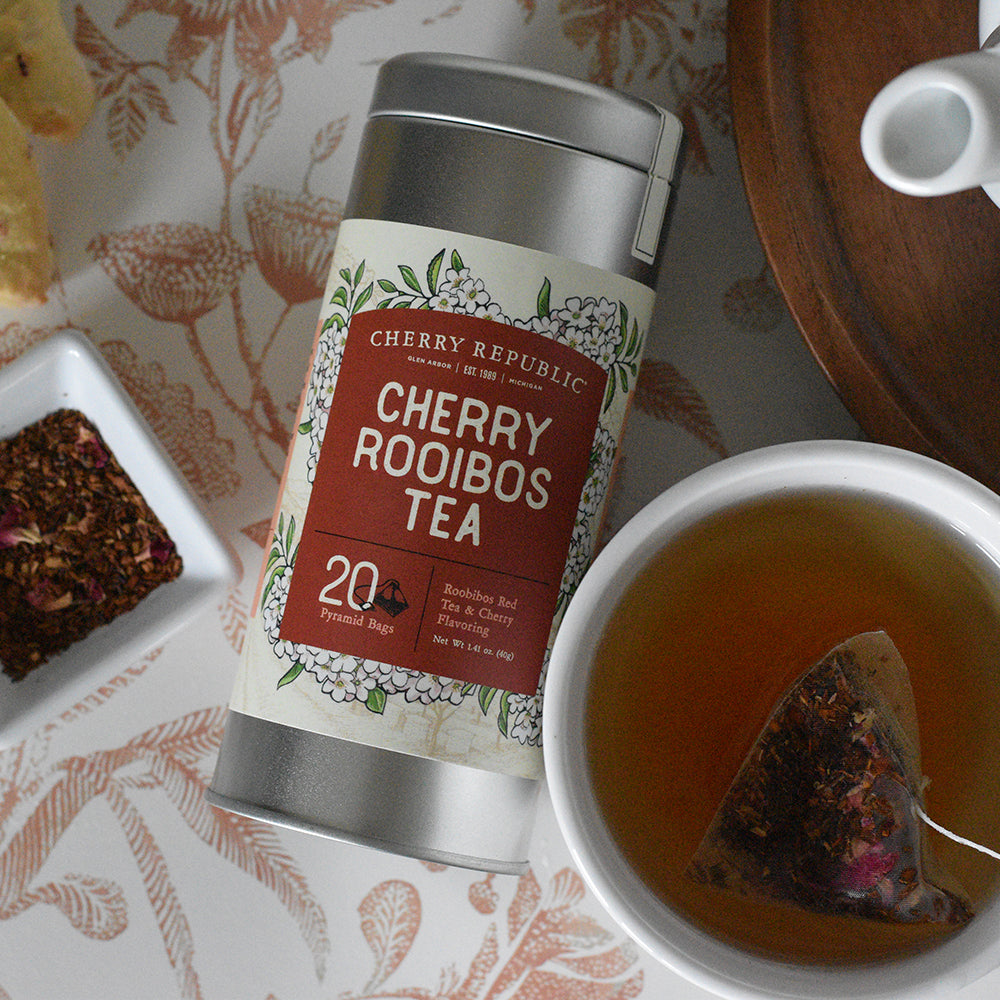 A tin of Cherry Republic cherry rooibos tea next to a cup of freshly brewed tea