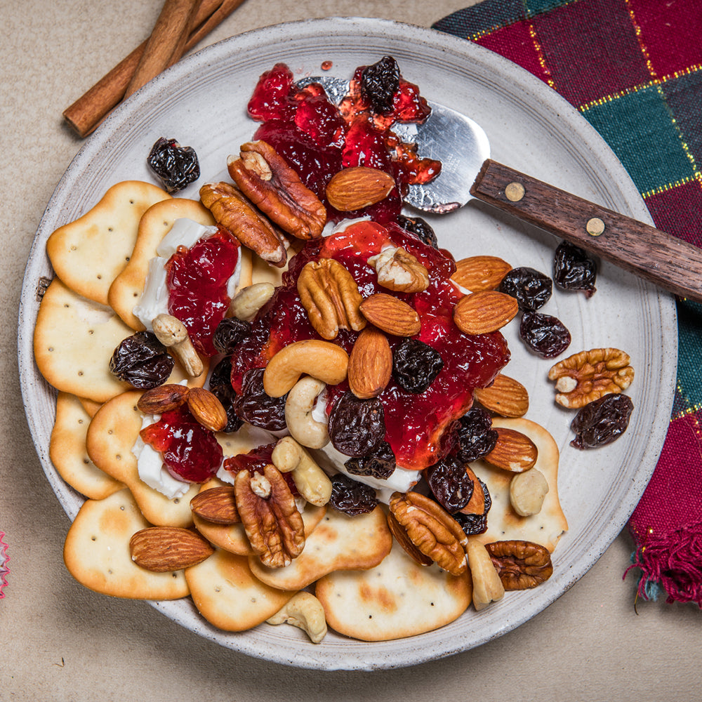 A colorful plate of crackers topped with nuts and dried fruit