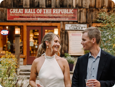 A bride and groom smiling outside the Great Hall of the Republic in Glen Arbor